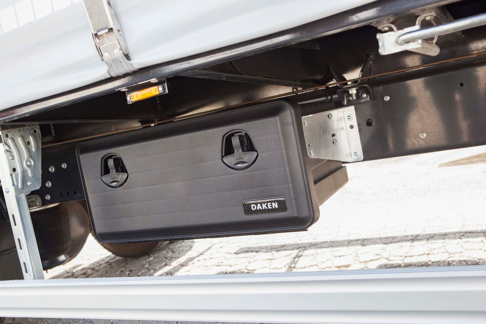 Daken Just - Cassetta porta attrezzi in plastica in primo piano, chiusa, di colore nero, installata su mezzo, foto frontale ravvicinata